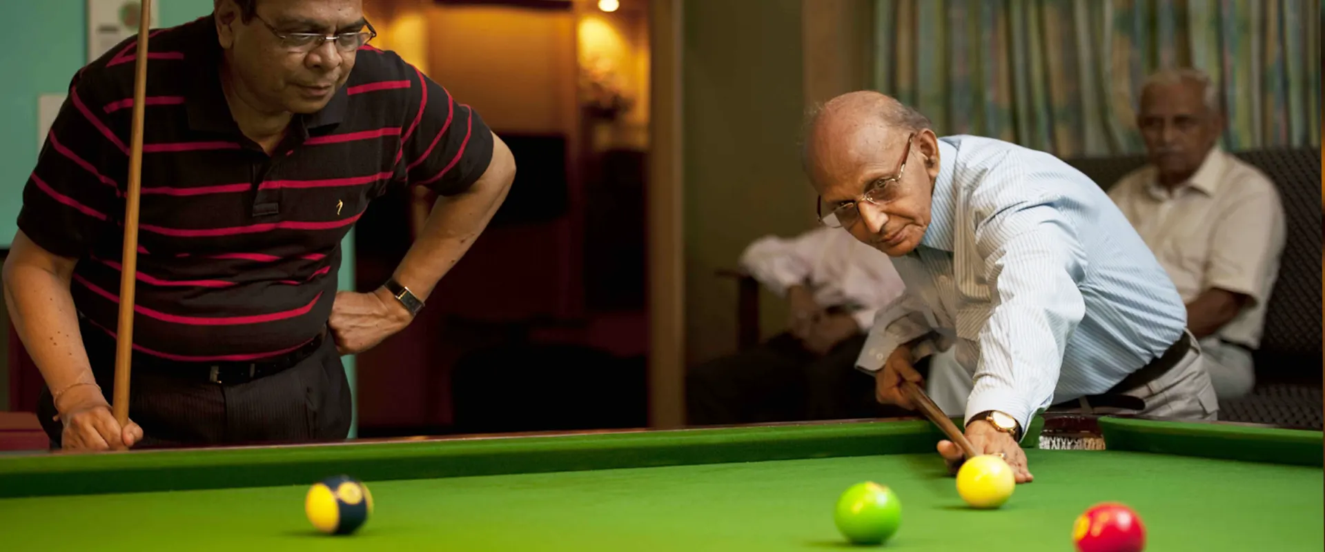 Two residents playing billiards in the games room at Jagriti Dham, watched by a third