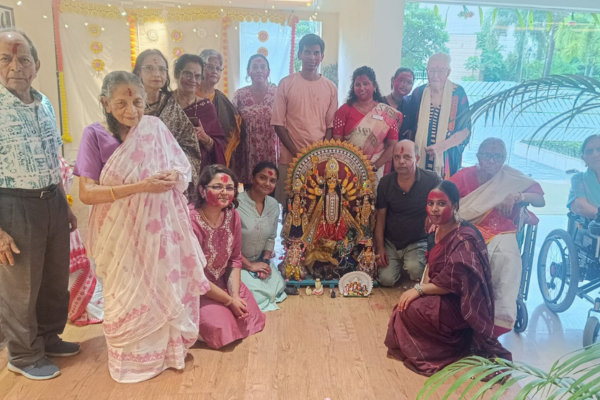 Residents of Jagriti Dham joyfully pose for a group photo around the Durga idol, with many faces showing traces of red sindoor from the Sindur Khela ceremony on Vijayadashami.