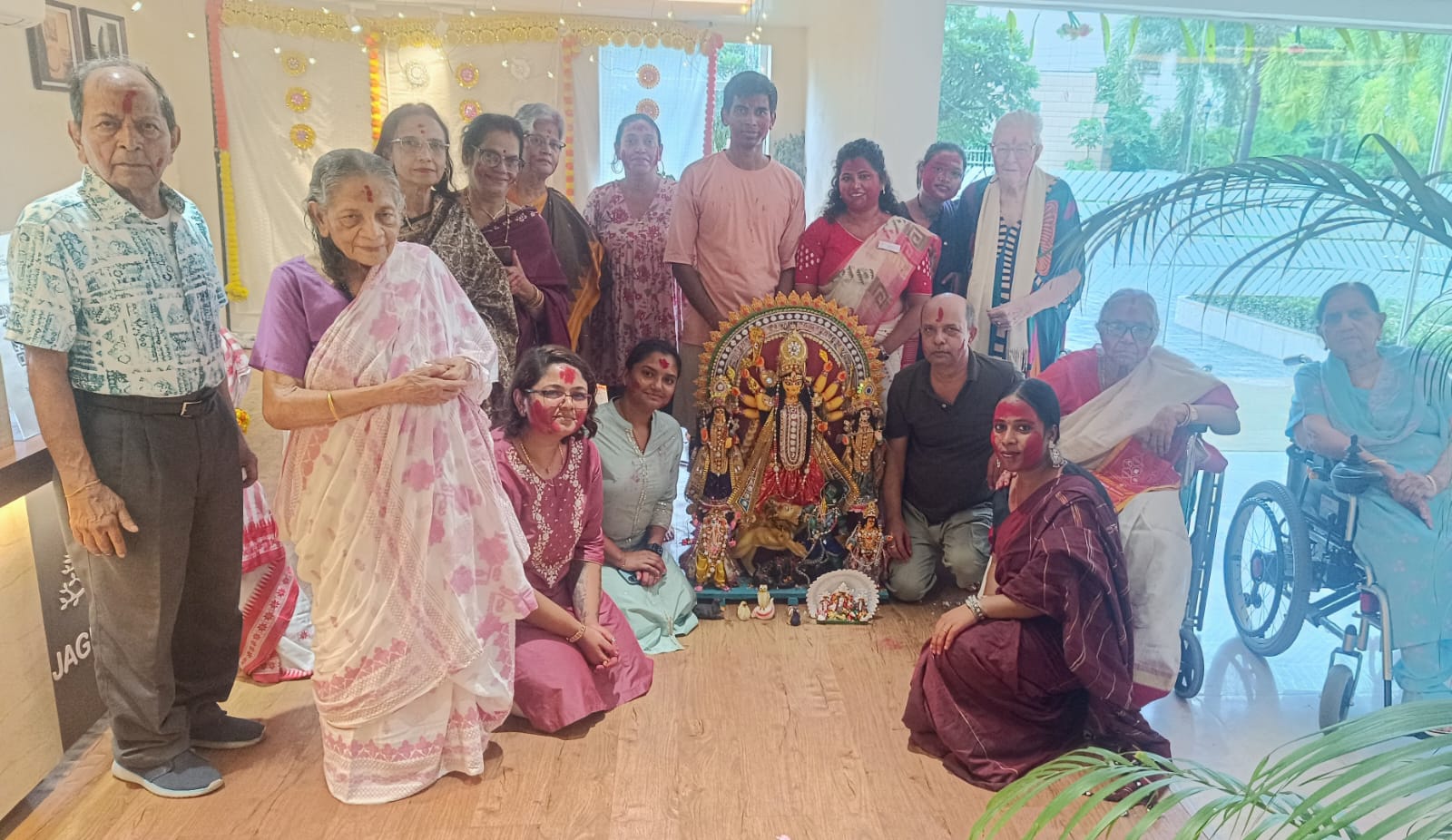 Residents of Jagriti Dham joyfully pose for a group photo around the Durga idol, with many faces showing traces of red sindoor from the Sindur Khela ceremony on Vijayadashami.