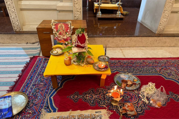 The sacred setup for the Kojagari Laxmi Puja celebration at Jagriti Dham, showing a framed image of Goddess Laxmi on a yellow altar, surrounded by traditional offerings like fruits, sweets, and glowing diyas, creating a devotional atmosphere for the residents.