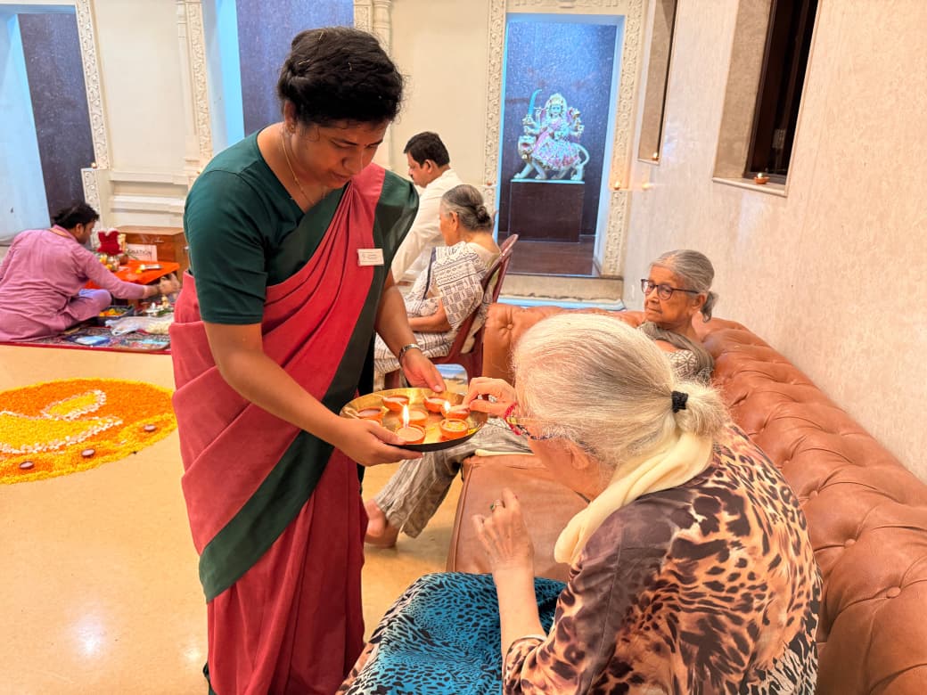 A caring staff member offers a lit diya to a senior resident during Diwali celebrations at Jagriti Dham, a luxurious old age home in Kolkata.