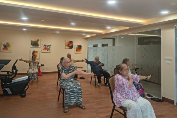 Senior citizens performing seated stretching exercises during a guided wellness class in a modern indoor fitness studio.