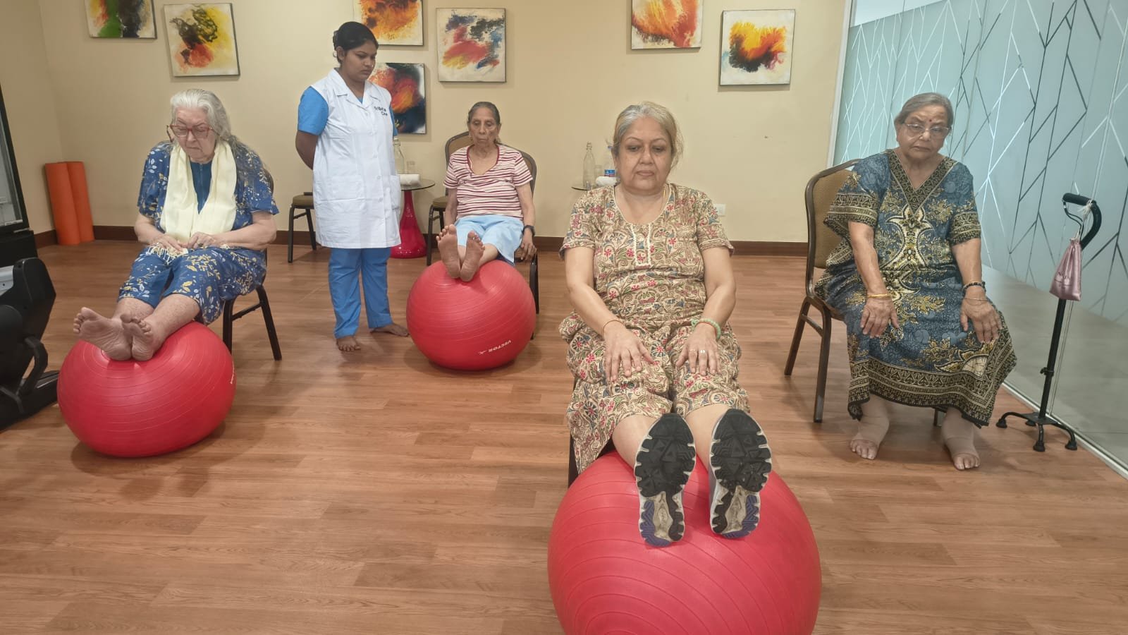 Elderly residents doing guided fitness exercises with a caregiver in a space designed around senior living architecture.
