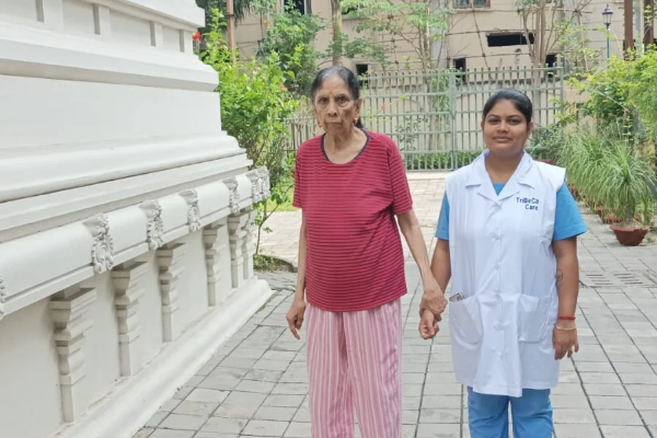 An elderly resident walking hand in hand with a caregiver, showing the support available when moving to a retirement community.